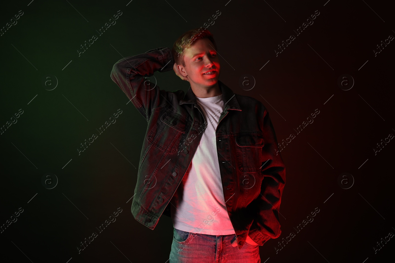 Photo of Smiling man wearing jacket in neon lights against black background