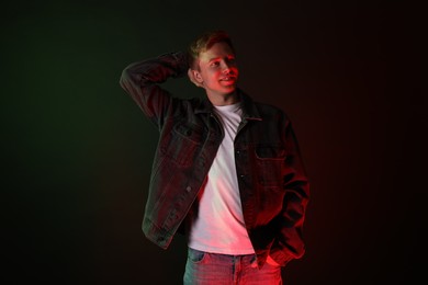 Photo of Smiling man wearing jacket in neon lights against black background