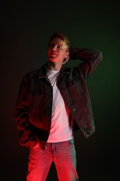 Photo of Smiling man wearing jacket in neon lights against black background