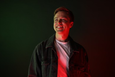 Photo of Smiling man wearing jacket in neon lights against black background