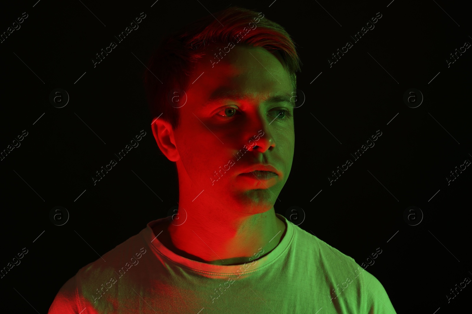 Handsome man in neon lights against black background Photo of Handsome man in neon lights against black background