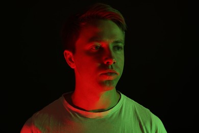 Photo of Handsome man in neon lights against black background