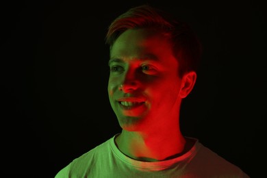 Photo of Smiling man in neon lights against black background
