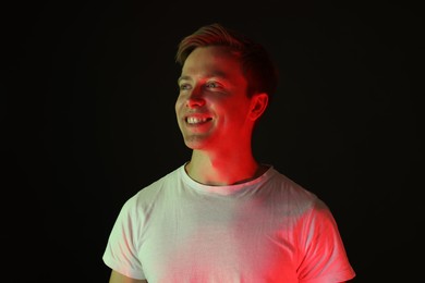Photo of Smiling man in neon lights against black background