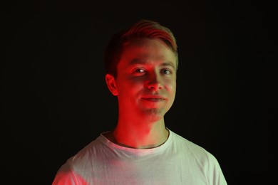 Photo of Portrait of handsome man in neon lights against black background