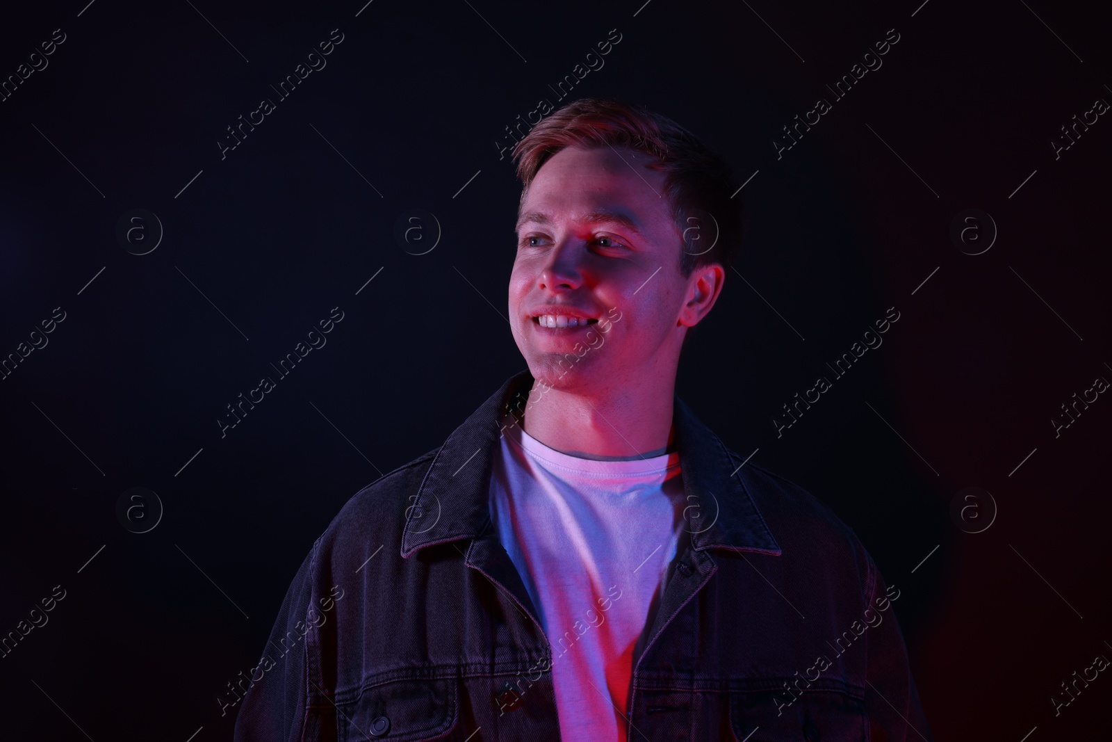 Smiling man in neon lights against black background Photo of Smiling man in neon lights against black background