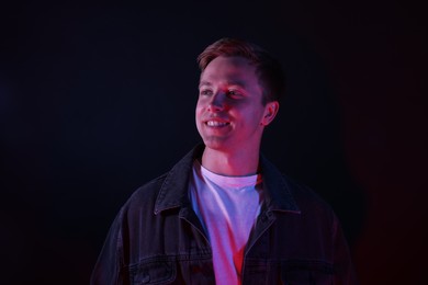 Photo of Smiling man in neon lights against black background