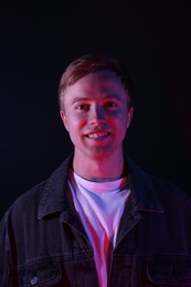 Photo of Portrait of smiling man in neon lights against black background