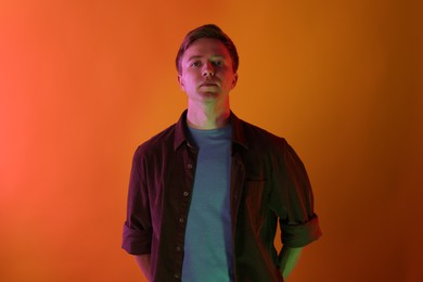 Photo of Portrait of handsome man in neon lights against orange background
