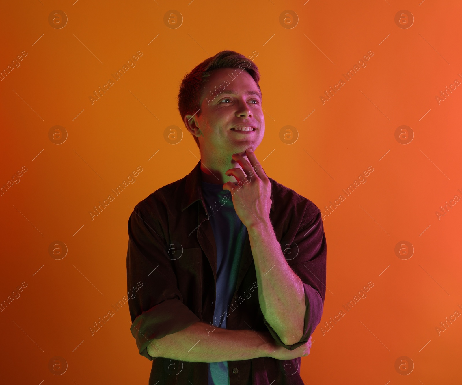 Photo of Smiling man in neon lights against orange background