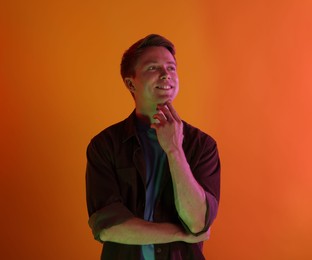Photo of Smiling man in neon lights against orange background