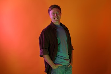 Photo of Portrait of smiling man in neon lights against orange background