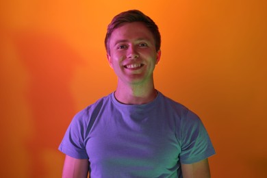 Photo of Portrait of smiling man in neon lights against orange background