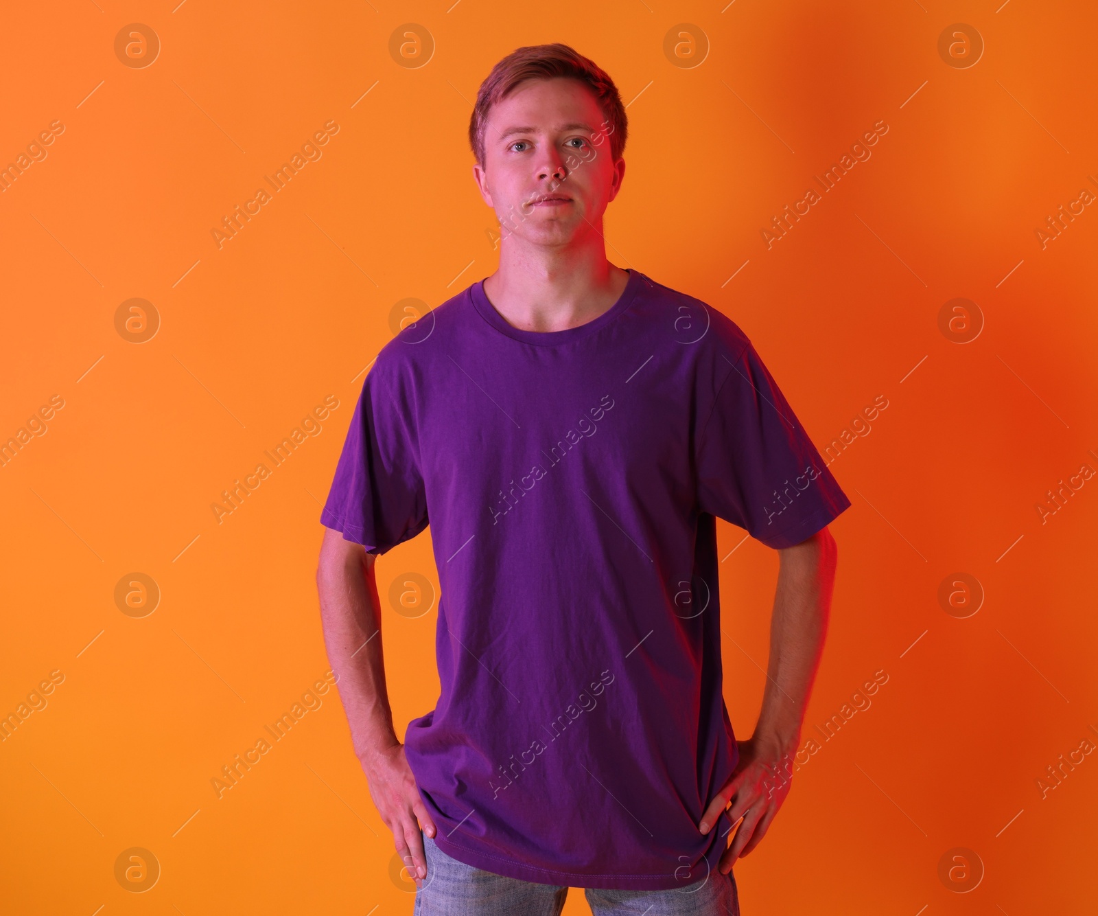 Portrait of handsome man in neon lights against orange background Photo of Portrait of handsome man in neon lights against orange background