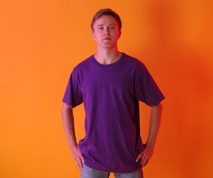 Photo of Portrait of handsome man in neon lights against orange background