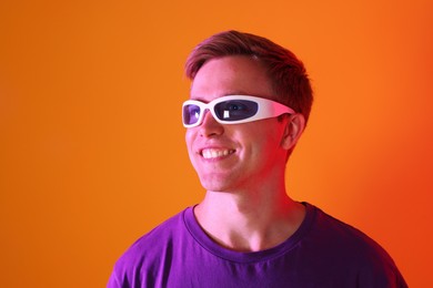 Photo of Smiling man wearing sunglasses in neon lights against orange background