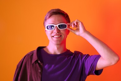 Photo of Smiling man wearing sunglasses in neon lights against orange background