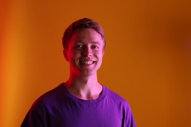 Photo of Portrait of smiling man in neon lights against orange background