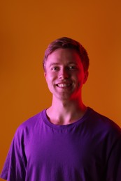 Photo of Portrait of smiling man in neon lights against orange background