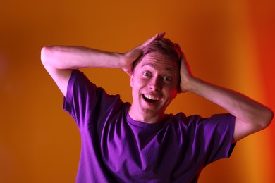 Photo of Emotional man in neon lights against orange background