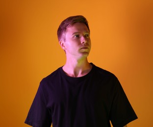 Photo of Handsome man in neon lights against orange background