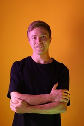 Photo of Portrait of smiling man in neon lights against orange background