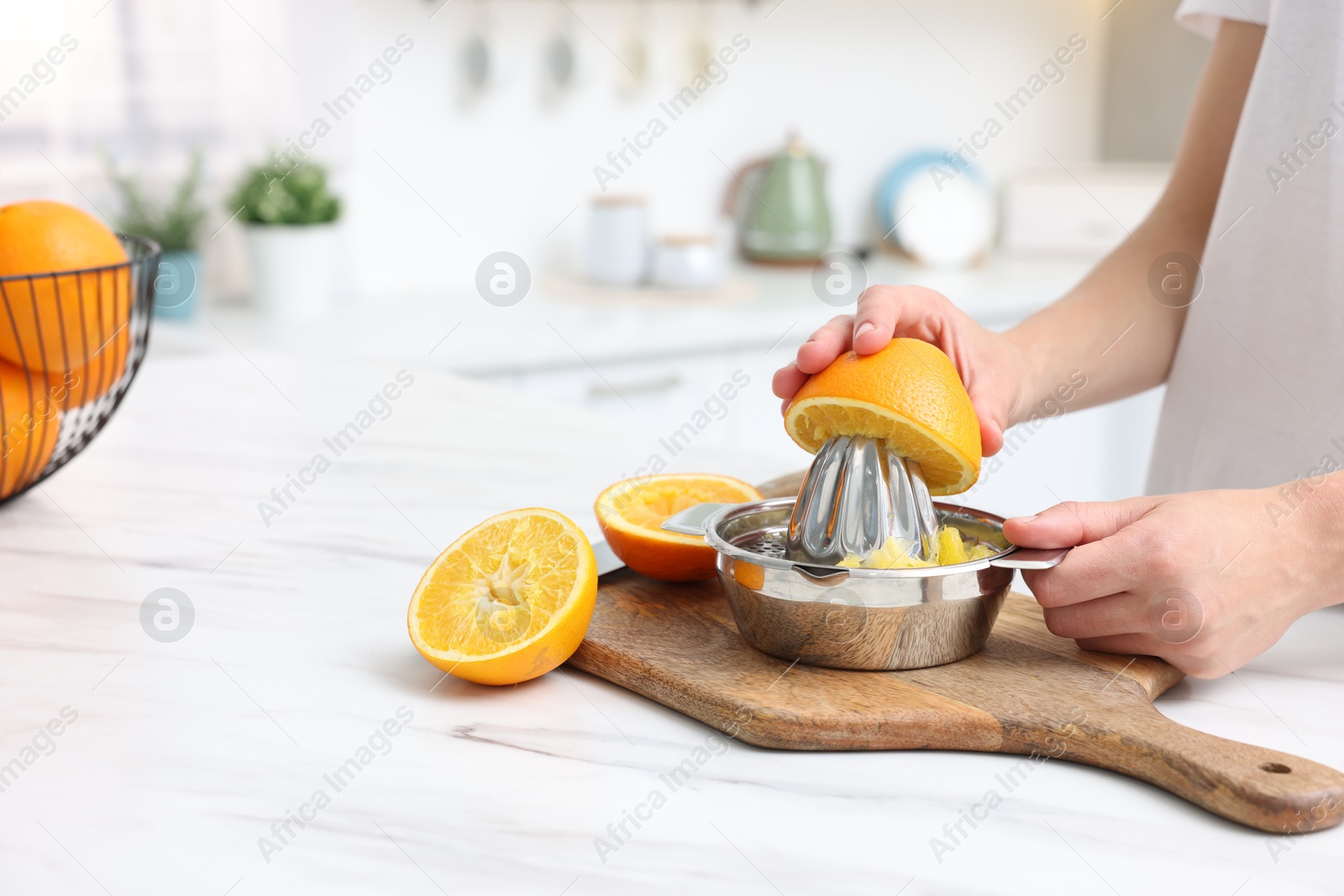 Making juice. Woman with orange using juicer at table indoors, closeup. Space for text Photo of Making juice. Woman with orange using juicer at table indoors, closeup. Space for text