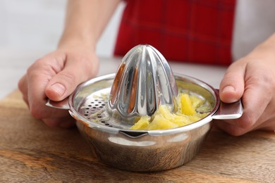 Photo of Making orange juice. Woman with juicer at table indoors, closeup