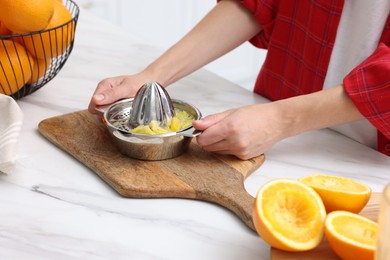 Photo of Making orange juice. Woman with juicer at white marble table indoors, closeup