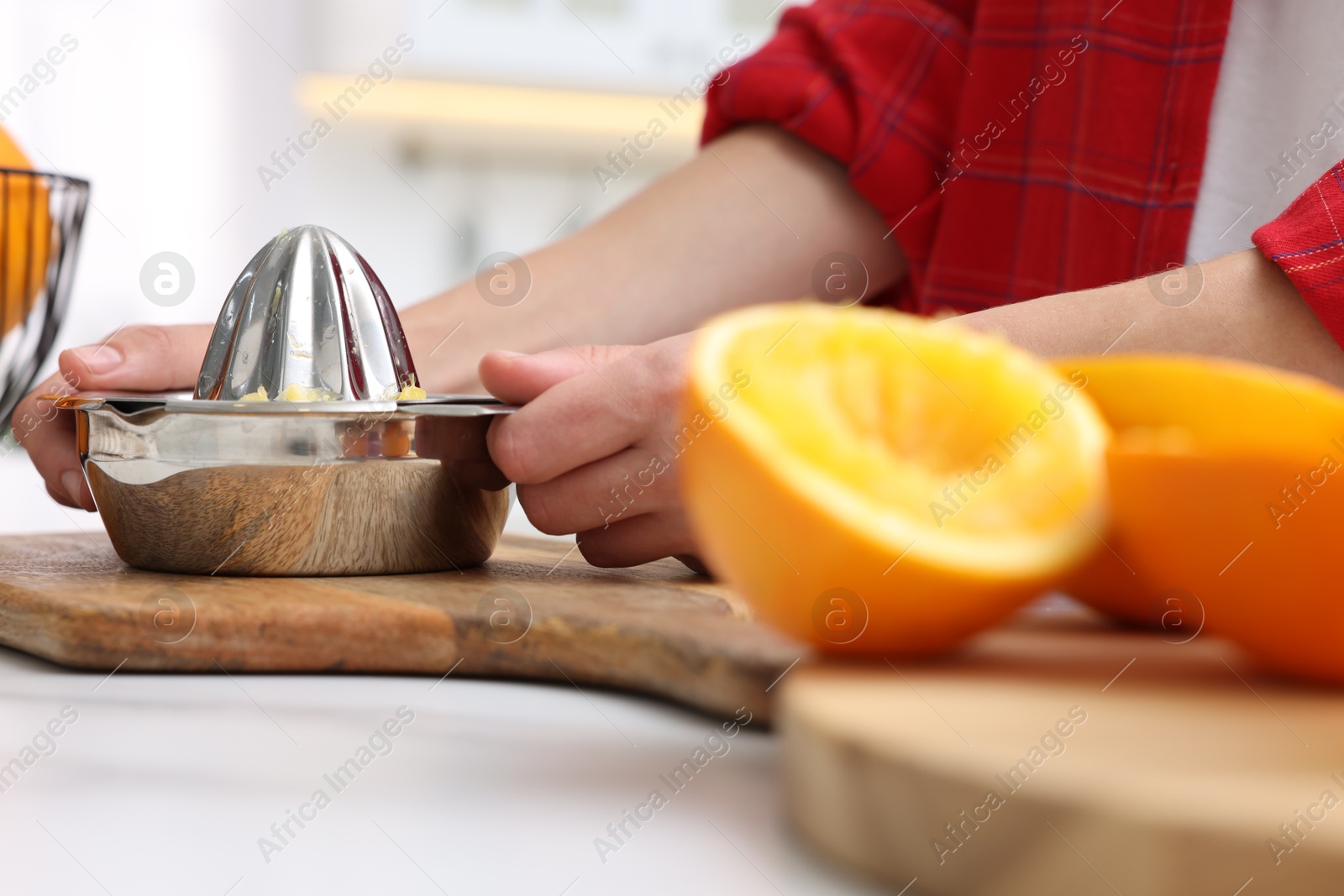 Making orange juice. Woman with juicer at white marble table indoors, closeup Photo of Making orange juice. Woman with juicer at white marble table indoors, closeup