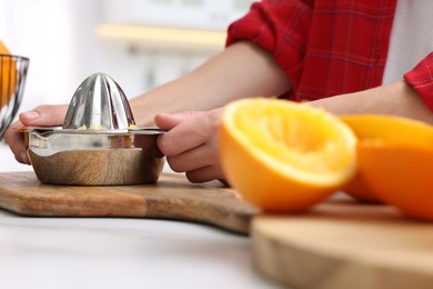 Photo of Making orange juice. Woman with juicer at white marble table indoors, closeup