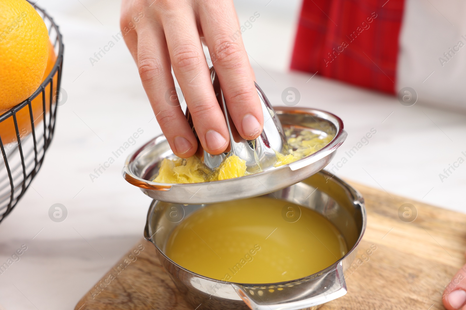 Woman with juicer and freshly squeezed orange juice at white marble table indoors, closeup Photo of Woman with juicer and freshly squeezed orange juice at white marble table indoors, closeup