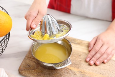Photo of Woman with juicer and freshly squeezed orange juice at white marble table indoors, closeup
