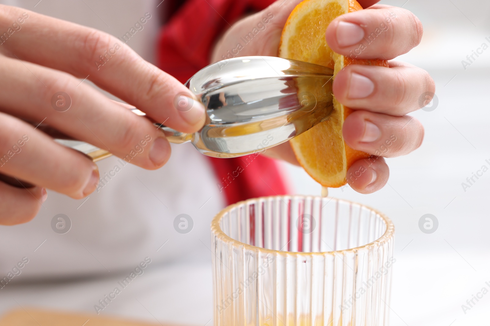 Making juice. Woman with orange using juicer indoors, closeup Photo of Making juice. Woman with orange using juicer indoors, closeup