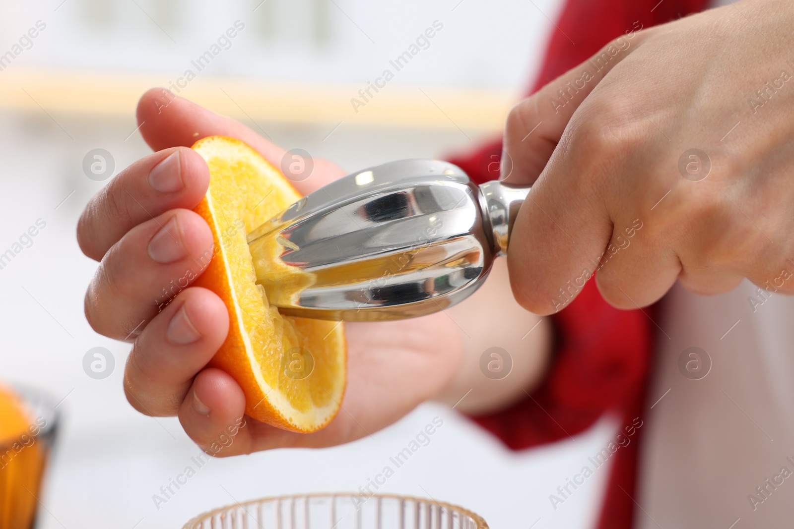 Making juice. Woman with orange using juicer indoors, closeup Photo of Making juice. Woman with orange using juicer indoors, closeup