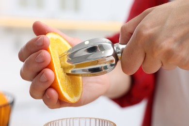 Photo of Making juice. Woman with orange using juicer indoors, closeup