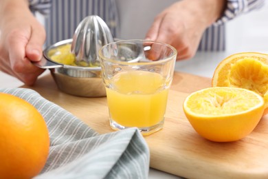 Photo of Woman with juicer and freshly squeezed orange juice at table indoors, closeup