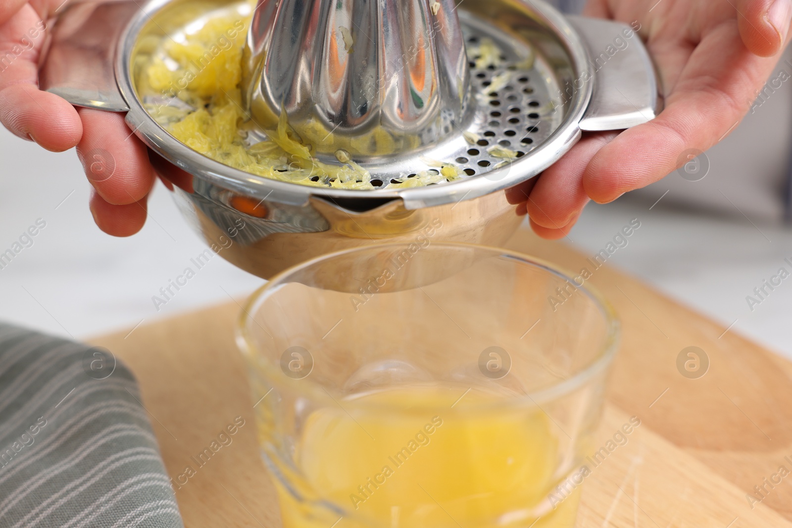 Woman pouring freshly squeezed orange juice into glass at table indoors, closeup Photo of Woman pouring freshly squeezed orange juice into glass at table indoors, closeup