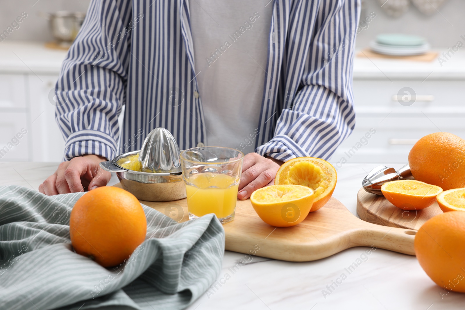 Woman with juicer, freshly squeezed orange juice and fruits at white marble table indoors, closeup Photo of Woman with juicer, freshly squeezed orange juice and fruits at white marble table indoors, closeup