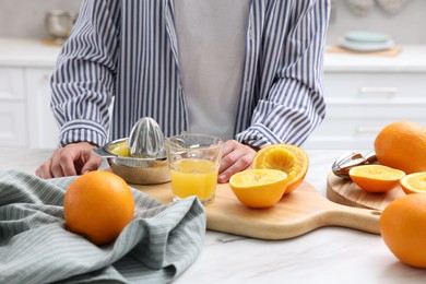 Photo of Woman with juicer, freshly squeezed orange juice and fruits at white marble table indoors, closeup