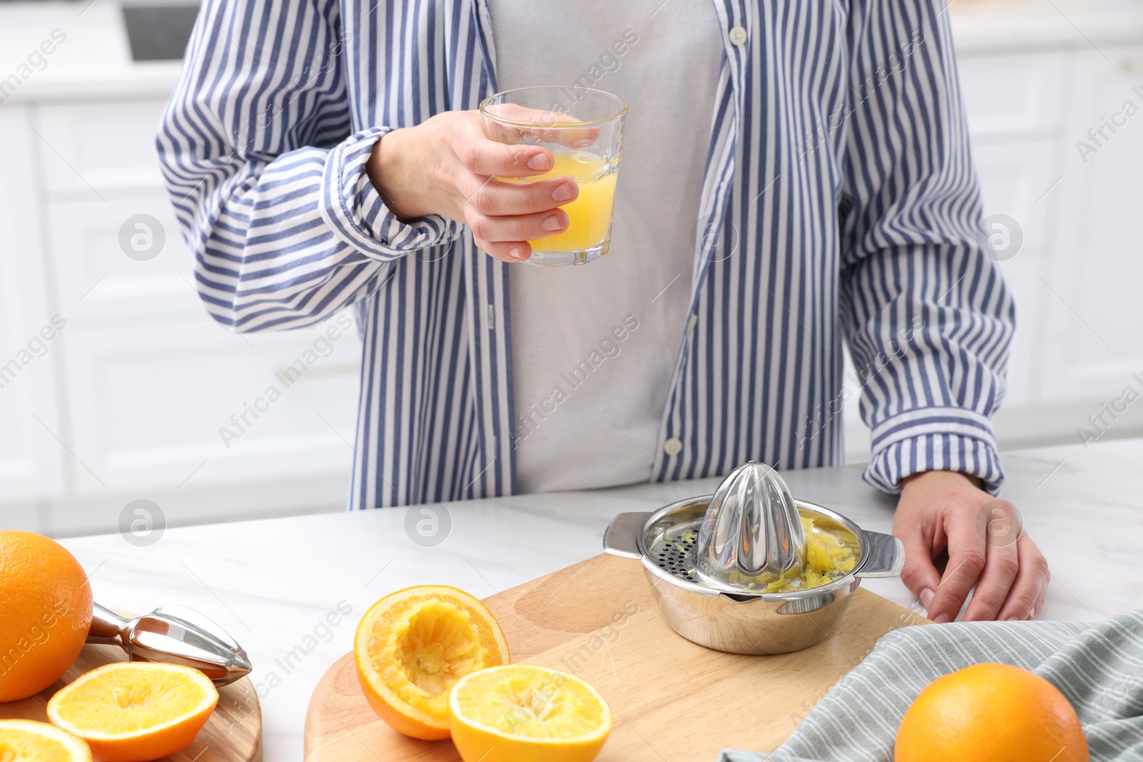 Woman with glass of freshly squeezed orange juice at white marble table indoors, closeup Photo of Woman with glass of freshly squeezed orange juice at white marble table indoors, closeup