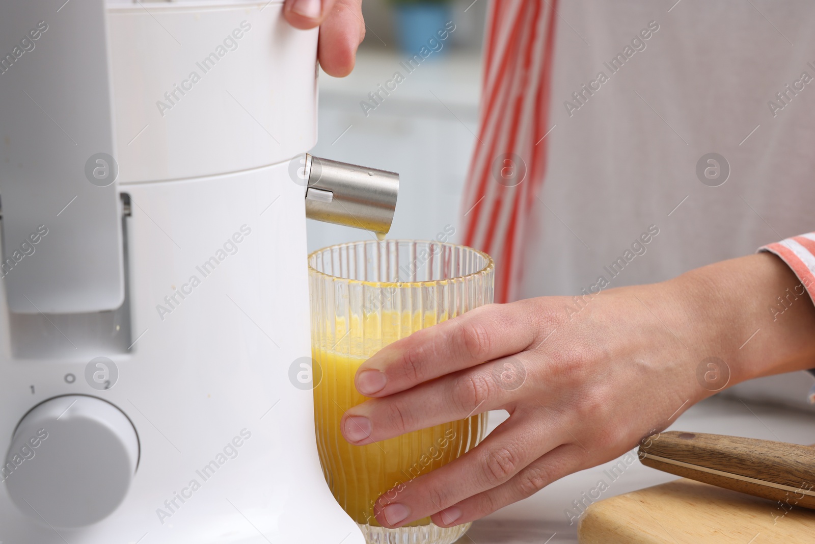 Photo of Woman making fresh orange juice with modern juicer at table indoors, closeup