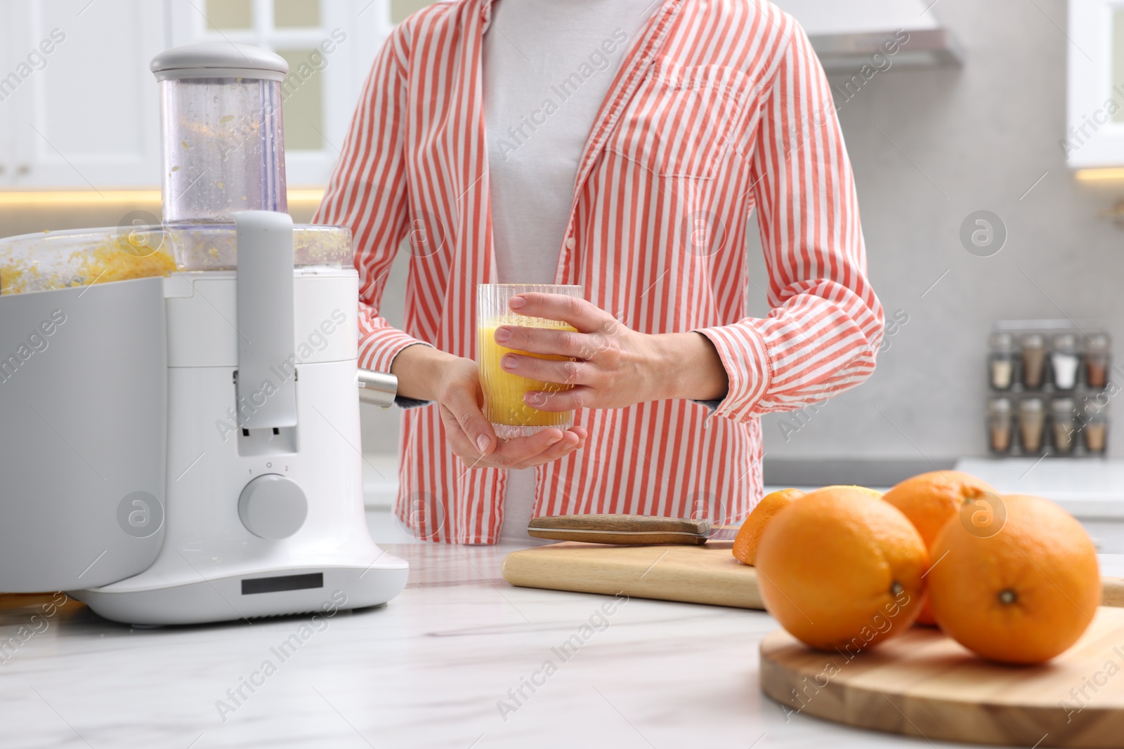 Woman with glass of freshly squeezed orange juice at white marble table indoors, closeup Photo of Woman with glass of freshly squeezed orange juice at white marble table indoors, closeup