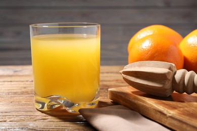 Photo of Freshly squeezed orange juice, fruits and juicer on wooden table, closeup