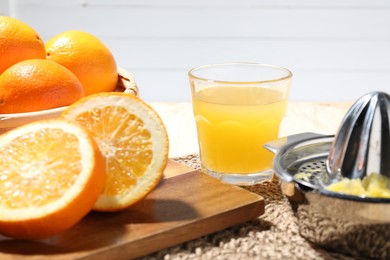 Photo of Freshly squeezed orange juice, fruits and juicer on table, closeup