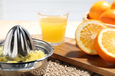 Photo of Freshly squeezed orange juice, fruits and juicer on table, closeup