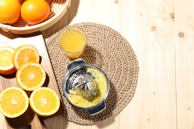 Photo of Freshly squeezed orange juice, fruits and juicer on wooden table, flat lay. Space for text