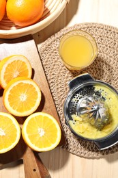 Photo of Freshly squeezed orange juice, fruits and juicer on wooden table, flat lay
