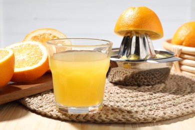 Photo of Freshly squeezed orange juice, fruits and juicer on wooden table, closeup