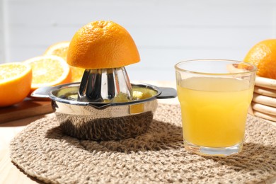 Photo of Freshly squeezed orange juice, fruits and juicer on table, closeup